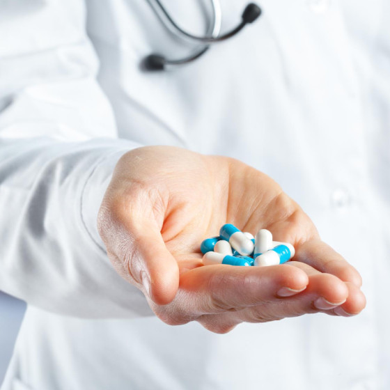 Doctor holding blue and white capsules in hand during medical consultation Doctor holding blue and white capsules in hand during medical consultation
